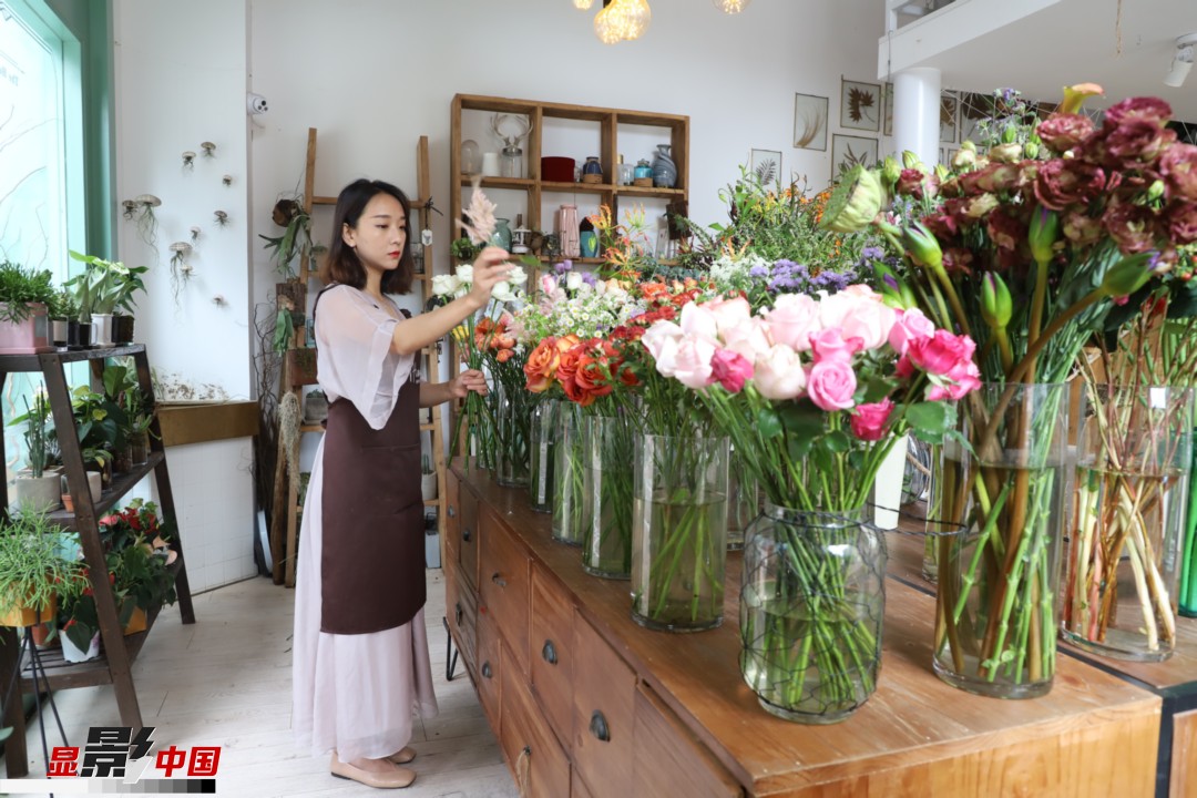 王黎媛是一名河南姑娘，在昆明念完大學(xué)后，就再也舍不下春城的藍(lán)天陽光、青山碧水，更舍不下這里的四時繁花，于是就干脆留了下來，成了一名媒體人。2017年的時候又毅然辭去工作，創(chuàng)業(yè)開起了花店，成了都市里的一名“花房姑娘”。圖為王黎媛在自己的花店中整理鮮花。新華網(wǎng) 周亞平/攝 念新洪/文